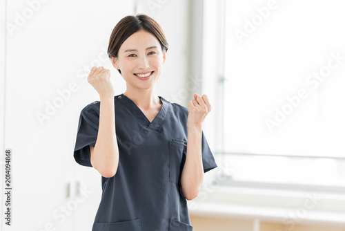 笑顔でガッツポーズをする元気な女性医療従事者・前向きな医療イメージ、