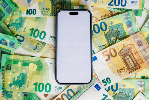 Top-down view of smartphone with white screen on euro cash surface. Concept digital banking and finance marketing.
