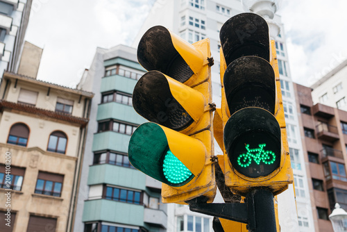 Tableau sur toile Green traffic light with bicycle symbol illuminated, set against a backdrop of m