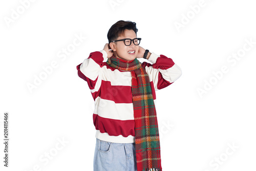 Tableau sur toile Annoyed Person Covering Ears: A young person wearing a striped sweater and plaid scarf, with glasses, covers their ears with a pained expression, possibly due to loud noise or an unpleasant situation