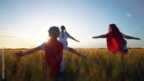 Superhero running through the wheat with his family. Child group superhero family concept. group of children are running together in a field. fun Superheroes run field of wheat children together.