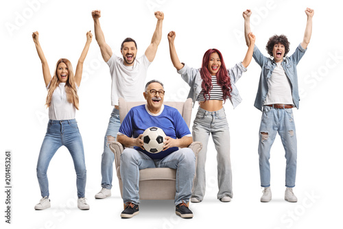 Man sitting in an armchair with a football and cheering with a group of young people