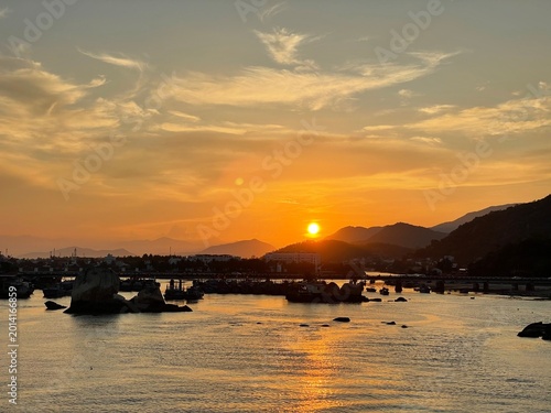 Foto Sunset beach with fishing boats, village and mountains, tranquil Southeast Asia