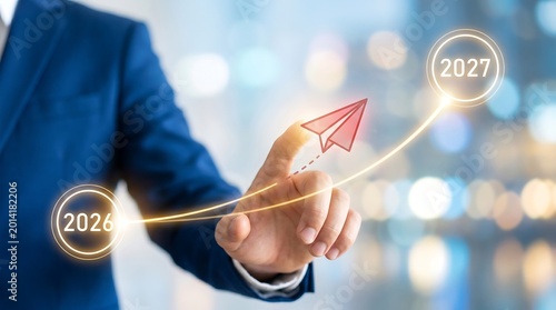Businessman's hand pointing at a glowing digital line graph with a red paper airplane symbolizing business growth and future planning for years 2026 and 2027