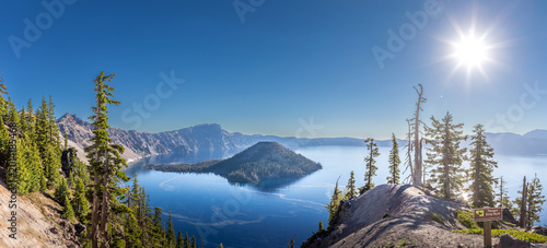 Tableau sur toile Deep blue Crater Lake surrounded by steep volcanic caldera cliffs with Wizard Is