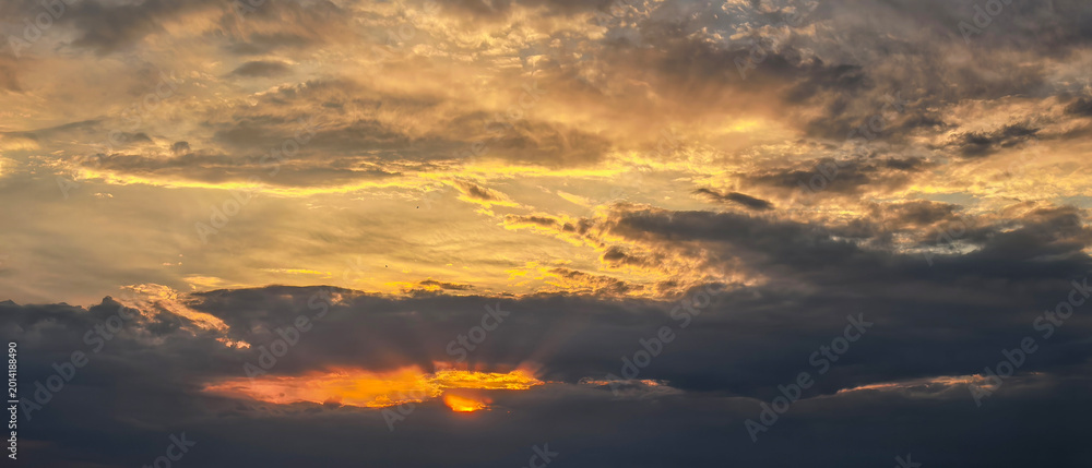 Fototapeta premium Golden Sunset Light Behind Dark Evening Clouds