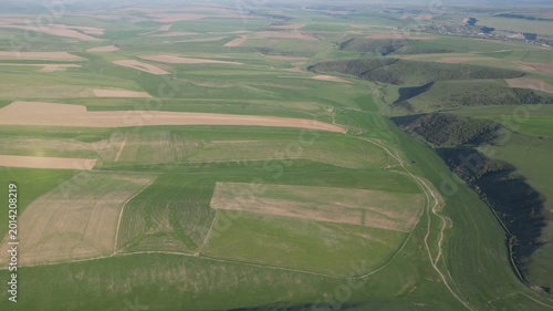 Aerial view of a lush valley featuring segmented fields and deep shadows.