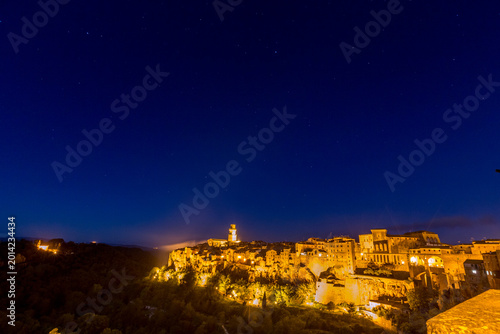 Nighttime view of town with a clock tower and stars in the sky, Sovana, Tuscany, Italy, long exposure motion blur