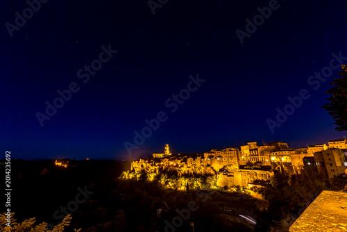 Nighttime view of a town with a clock tower and street light, Sovana, Tuscany, Italy, long exposure motion blur