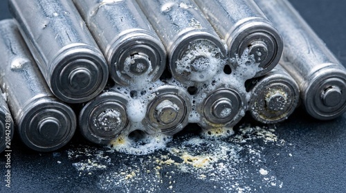 Concept of the dark side of green tech featuring damaged lithium-ion cells with toxic chemical leakage, illustrating EV battery pollution and e-waste management crisis