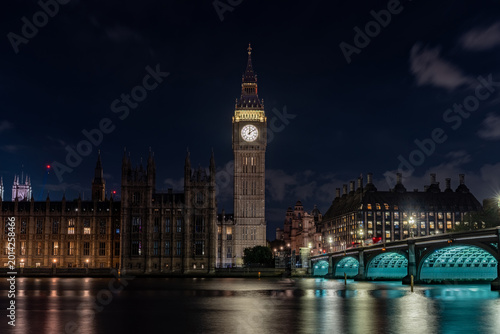 London United Kingdom 00.09 illuminated clock tower riverside government buildings reflection water night skyline historic architecture bridge landmark.