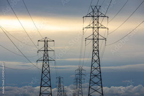 High-voltage transmission towers and power lines stretch into the distance beneath a dramatic overcast sky. Palo Alto Baylands, Santa Clara County, California.