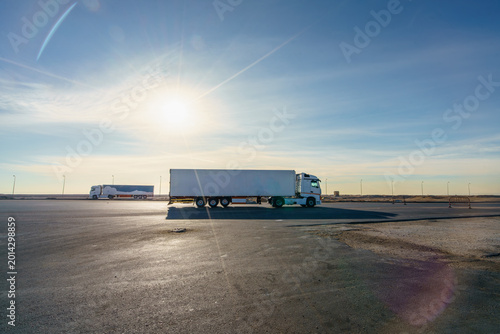Two white semi trucks parked at a highway rest stop between Hurghada and Cairo, Egypt, under a bright sunny sky.