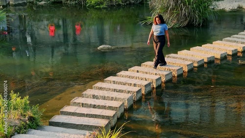 Young chinese woman walking over stepping stones in Furong