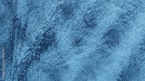 Extreme macro close-up of cracked blue melting ice texture in time lapse. Abstract frozen water surface with translucent crystal patterns, condensation and thawing details in studio lighting.