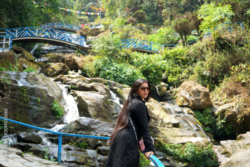 Foto Stylish woman posing by the rocky waterfall at the Rock Garden in Darjeeling Ind