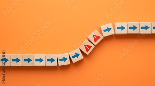 Risk management and crisis warning concept with wooden domino blocks turning corner on orange background, business challenge, change, and disruption