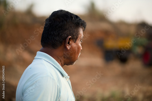 Man looks into the distance at a construction site during the late afternoon near a rural area in India