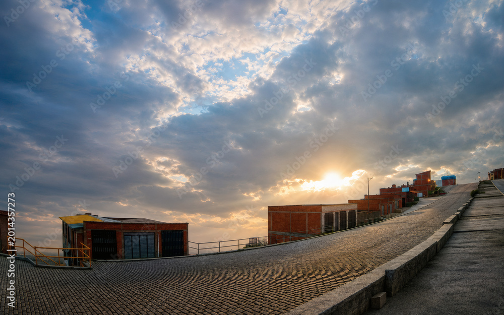 Obraz premium Dramatic sunset over residential urban street with cloudy sky