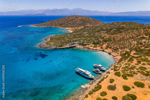 Fotografia Drone shot of tourist boats anchored in a crystal clear blue bay in Crete, Greec