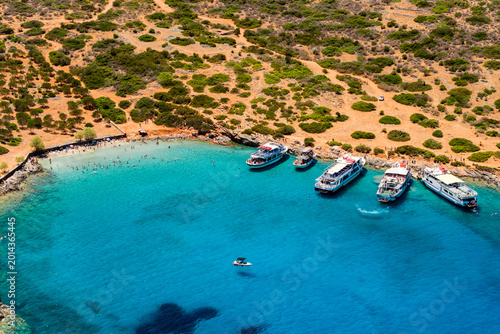 Fotografie Tourist excursion boats anchored in clear blue water of a Mediterranean bay