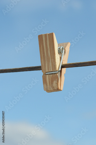Wooden clothespins on the rope against the blue sky background.