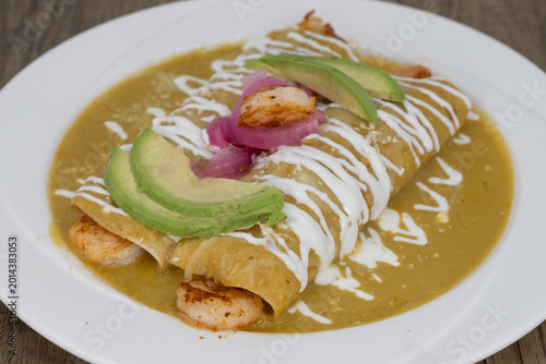 Foto Hearty plate of shrimp enchiladas smothered in green sauce and sour cream to sat