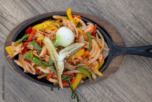 фотографія Overhead view of sizzling hot plate of chicken fajitas smothered in sauteed vege