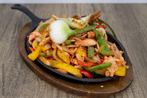 Bild auf Leinwand Sizzling hot plate of chicken fajitas smothered in sauteed vegetables to satisfy