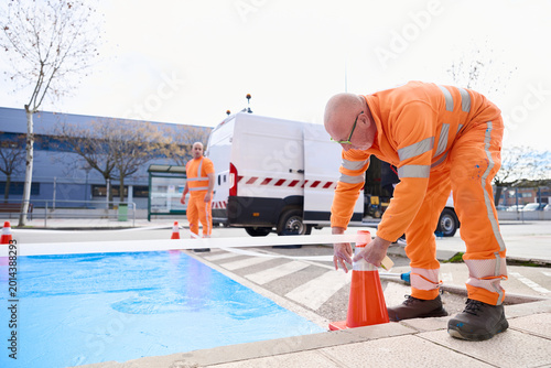 Foto Workers place cones and tape around a newly painted blue parking space on the street to secure the area and ensure safety while the marking dries