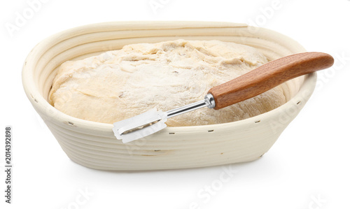Slika na platnu Raw sourdough bread in proofing basket and lame isolated on white