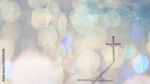 Crucifix standing while bokeh lights shifting, shadow casting down-left, revealing sky and water