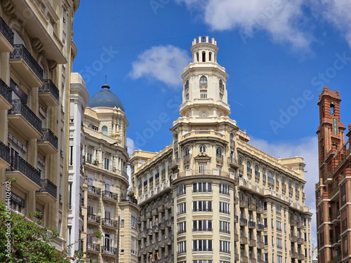Fotografie Wide view of Plaza del Ayuntamiento in Valencia, Spain, with pedestrians strolling between ornate buildings