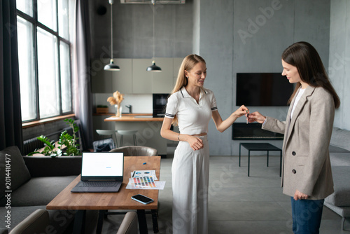 Real estate agent hands keys to smiling female client in a modern urban apartment, celebrating successful purchase or rental and the start of new ownership and contemporary city living