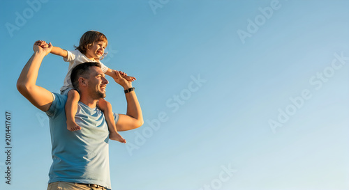 father carrying son on shoulders outdoors