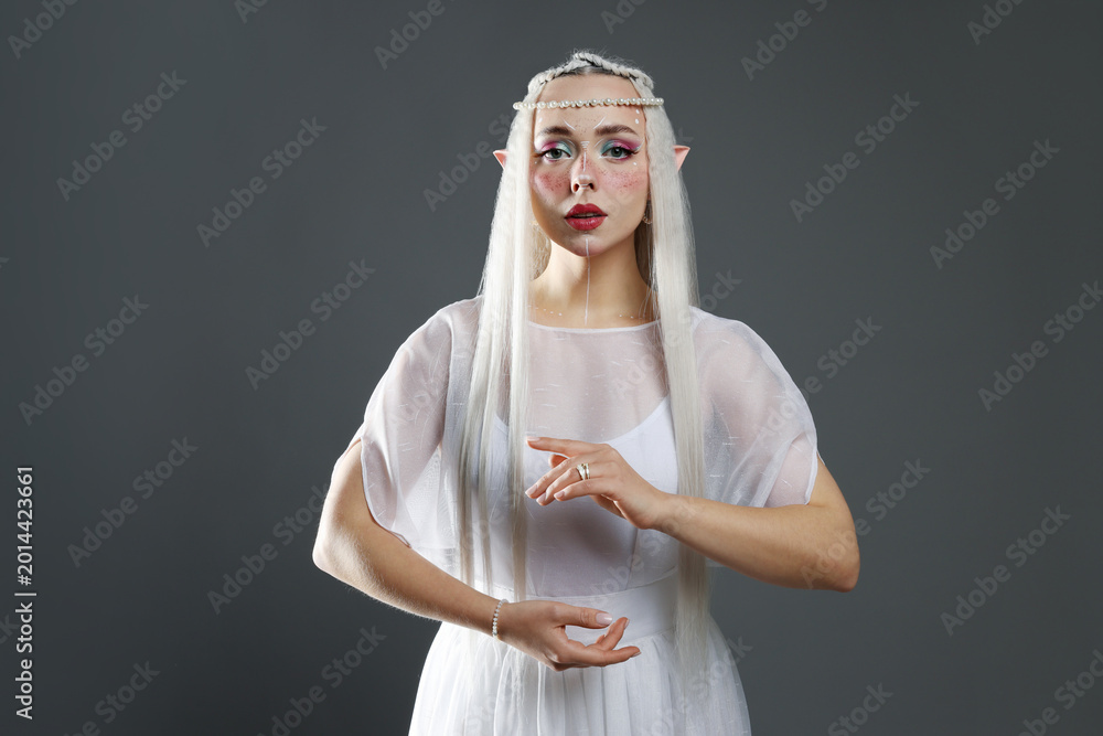 Fototapeta premium Beautiful girl dressed as elf on grey background