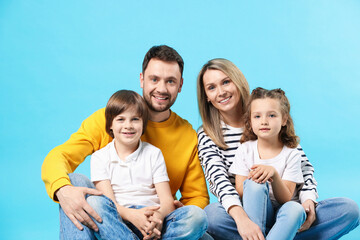Happy parents and their kids on light blue background