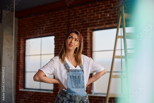 Tableau sur toile Displeased woman feeling uncertain while standing at her renovating home