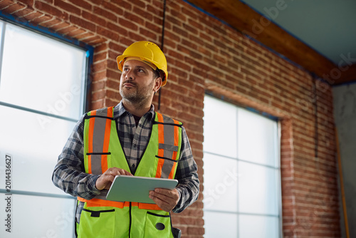 Bilde på lerret Construction worker using touchpad while working on home renovating project