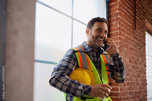 Canvastavla Happy construction site foreman talking on cell phone.