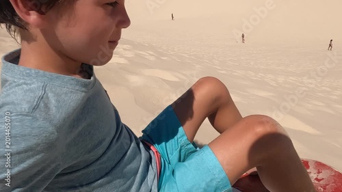 Young boy getting started slidding down sand dunes in South America