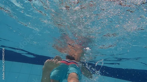 Young boy swimming in outdoor pool in summer - underwater unique angle