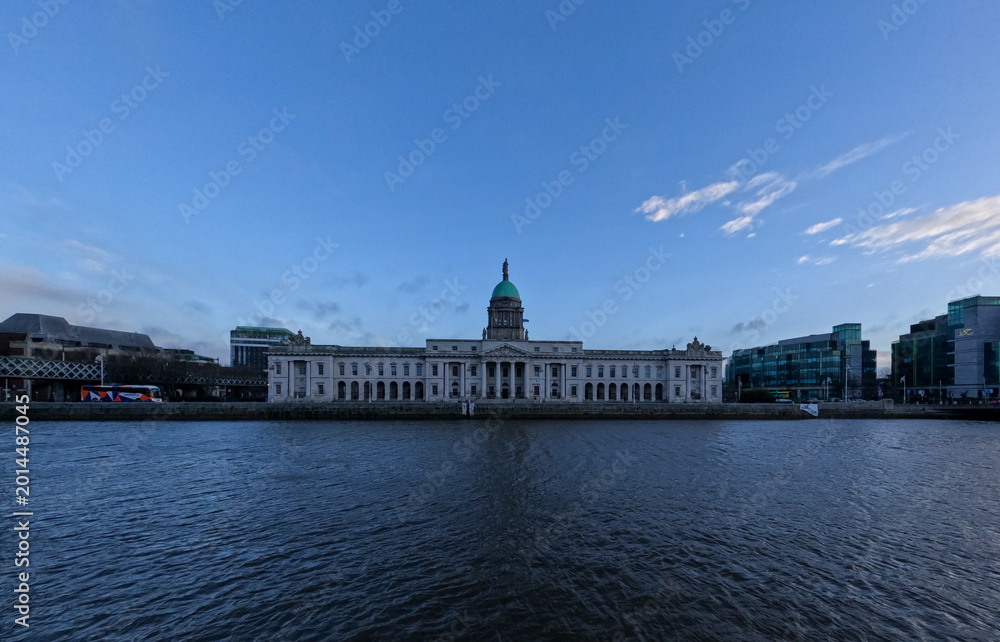 Fototapeta premium Custom House Dublin Ireland Across River Liffey with Neoclassical Architecture and Calm Water Under Clear Sky