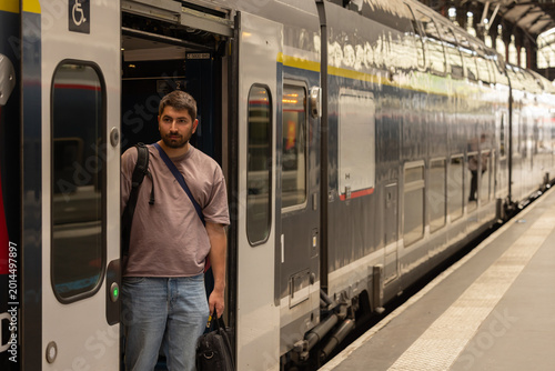 Schilderij op canvas Voyageur descendant d’un train en gare avec sac à dos et bagages