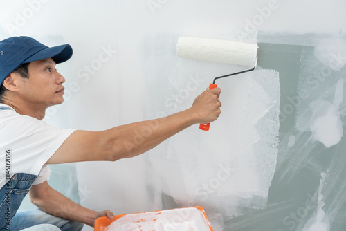 Photos painter man, brush in hand for products to restore and paint the wall, indoor th