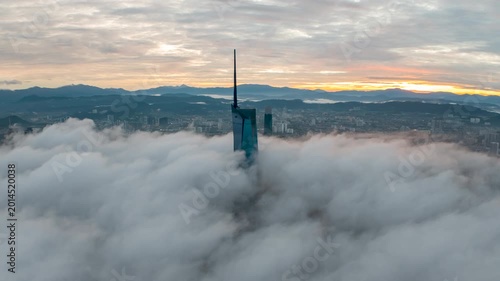 Aerial view time lapse 4k video of Kuala Lumpur city center view during dawn overlooking the city skyline in Federal Territory, Malaysia with epic low cloud glows on sunrise. Zoom out