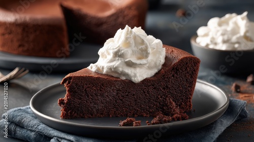 Rich chocolate cake slice with whipped cream and dark background