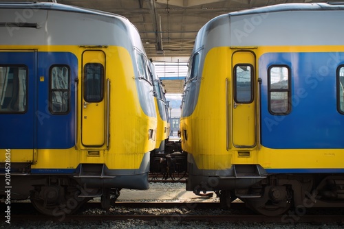 Two train cars with blue and yellow design at a station