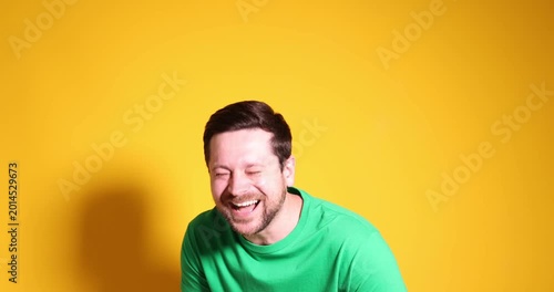 Man laughing and pointing at something on yellow background