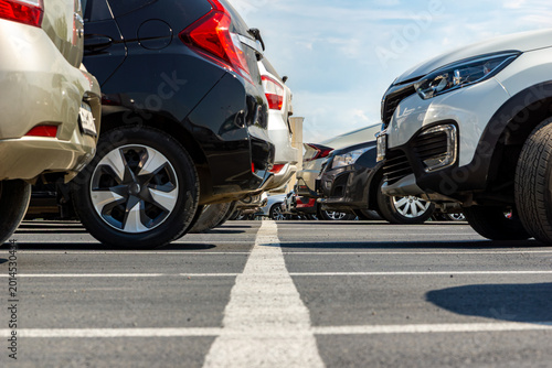 Cars parked in rows with white lines on asphalt seen from ground level